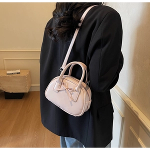 Detailed back view of pink bow handbag styled over a black blazer for modern contrast
