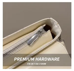Detailed close-up of premium silver zipper and D-ring on a cream baguette handbag