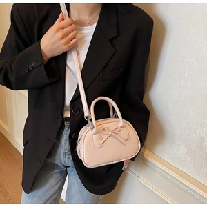Detail showing pink glossy bow bowling bag worn by model with adjustable strap