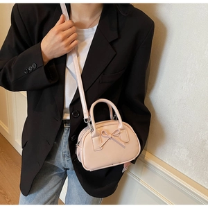 Pink bow handbag with adjustable shoulder strap shown worn crossbody on female model