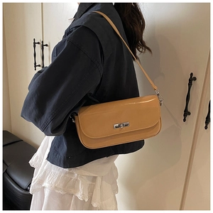 Detail of caramel brown minimalist crossbody bag with silver metallic twist lock closure