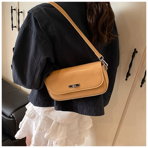 Detail of camel leather baguette bag with silver twist lock worn by a model in denim