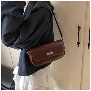 Detail of a brown glossy leather baguette bag with silver metallic twist lock closure