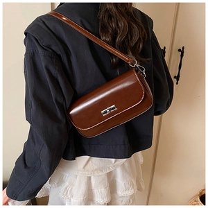 Detail of a dark brown glossy baguette bag featuring a silver rectangular metal clasp