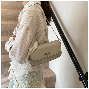 Detail of a beige faux leather shoulder bag with a silver-tone metal turn-lock closure