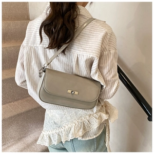 Detail of light grey leather baguette bag featuring a silver twist lock and matte finish