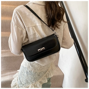 Rear view of a model carrying the black glossy faux leather shoulder bag on a staircase