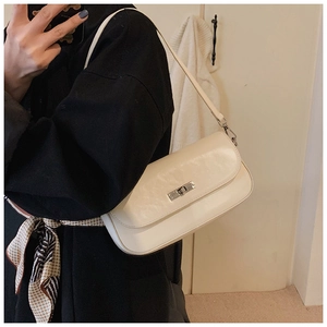 Close-up of creamy faux leather baguette bag with metallic buckle and shoulder strap detail