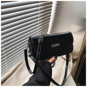 Detail of glossy black leather handbag with silver metal turn-lock and detachable strap