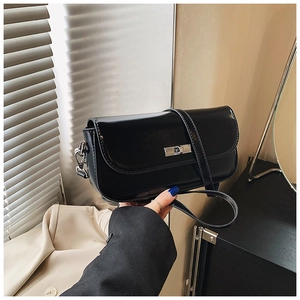 Close-up of black leather baguette bag featuring a silver rectangular twist lock closure