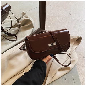 Detailed view of vintage brown leather bag with silver twist lock and mirror reflection