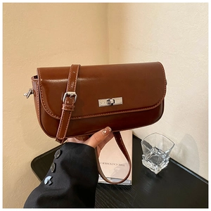 Detail of vintage brown baguette bag with glossy leather texture and silver turn-lock