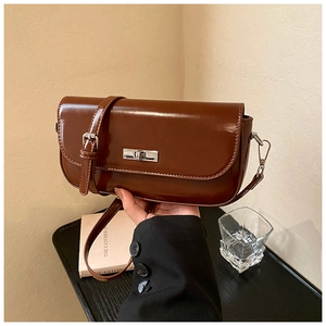 Detail of vintage brown glossy leather bag featuring a polished silver metallic swivel lock