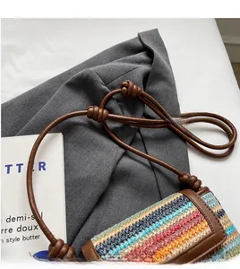 Detail of colorful woven crossbody bag featuring a knotted brown leather shoulder strap