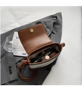 Detail showing the spacious interior of the straw crossbody bag with brown leather flap