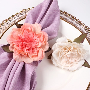 Close-up of elegant eucalyptus and peony napkin rings on a white porcelain dinner plate