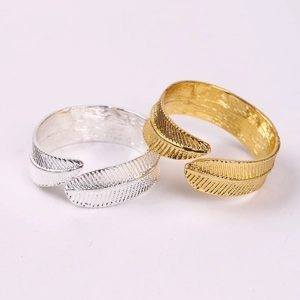 Elegant gold and silver leaf feather napkin rings with intricate metallic textures