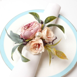 Detail of pink fabric rose napkin ring with champagne flowers and pearl on white plate