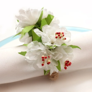 Detail of white artificial rose napkin ring with red stamens and woven hemp base