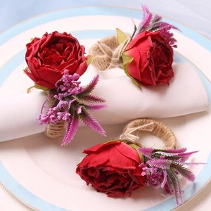 Close-up of red rose napkin rings with hemp rope weave on an elegant white napkin