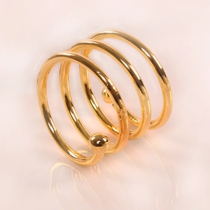 Macro detail of gold spiral napkin ring with three layers and smooth metal bead ends