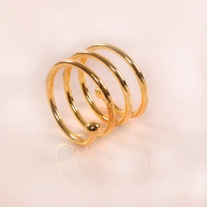 Macro shot of gold spiral napkin ring with ball ends on a reflective surface