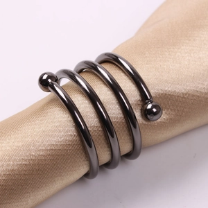 Macro shot of gun-black spiral napkin ring with glossy finish on gold satin background