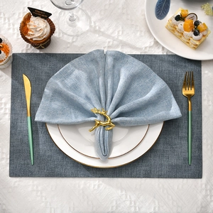 Close-up of a golden reindeer napkin ring on a light blue napkin for Christmas table decor