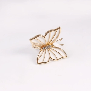 Detalle de servilletero mariposa dorada con esmalte blanco y pedrería brillante elegante