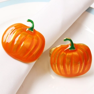 Detailed close-up of glossy orange pumpkin napkin rings on a white cloth and ceramic plate