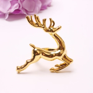 Macro detail of polished gold reindeer napkin ring on a minimalist elegant tabletop