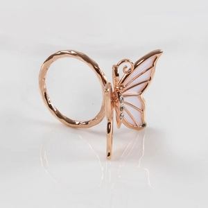 Detalle macro de servilletero de mariposa oro rosa con alas de nácar y cristales brillantes