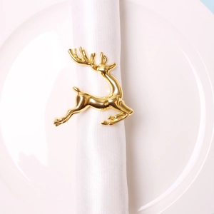 Close-up of golden reindeer napkin ring on white cloth and plate for festive dining