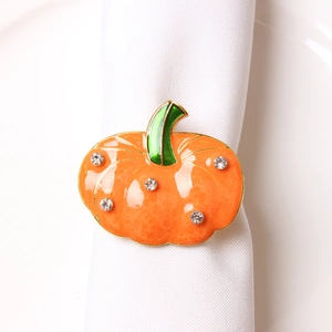 Detail of orange enamel pumpkin napkin ring with sparkling crystals on a white napkin