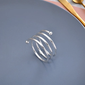 Elegant gold plated spiral napkin ring with double beads on a minimalist dinner plate