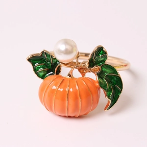 Golden pumpkin napkin ring with orange enamel, green leaf, and white pearl detail