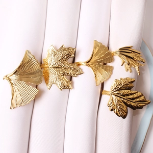Detailed close-up of golden leaf napkin rings on white cloth for table decoration