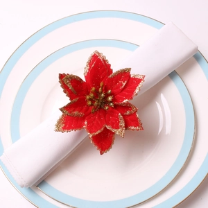 Rond de serviette poinsettia en velours rouge avec paillettes dorées sur assiette