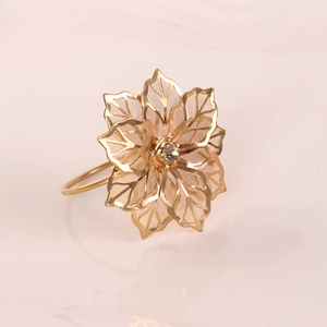 Dettaglio portatovagliolo a fiore dorato con petali traforati e strass centrale