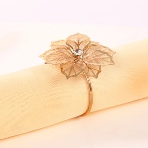 Dettaglio portatovagliolo dorato a forma di fiore con petali traforati e strass lucido