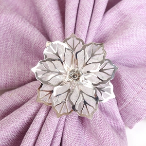 Dettaglio portatovagliolo a fiore argento con petali traforati e cristallo centrale