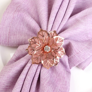 Dettaglio portatovagliolo a fiore in oro rosa con petali traforati e centro in cristallo