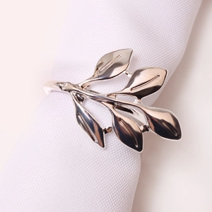 Polished silver leaf napkin ring with elegant branch design on a white cloth napkin