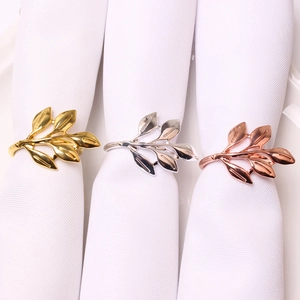 Close-up of gold, silver, and rose gold leaf napkin rings with detailed metal textures