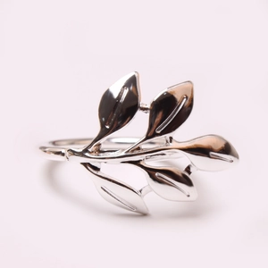 Macro shot of silver metal leaf napkin ring with intricate feather texture on pink