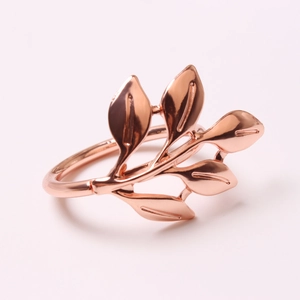 Close-up of rose gold leaf napkin ring with detailed vine and leaf texture on pink base