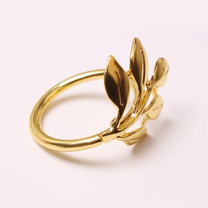 Detailed view of polished golden metal napkin ring in an elegant olive leaf design