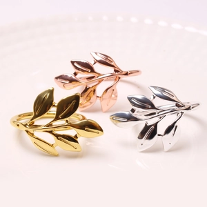 Detail view of gold, silver, and rose gold leaf napkin rings on white ceramic plate