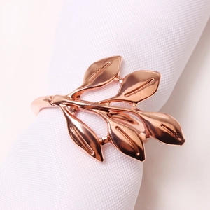 Elegant rose gold leaf napkin ring in branch shape on white fabric for dining