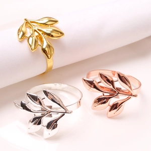 Detail of five-petal leaf napkin rings in gold, silver, and rose gold polished finishes